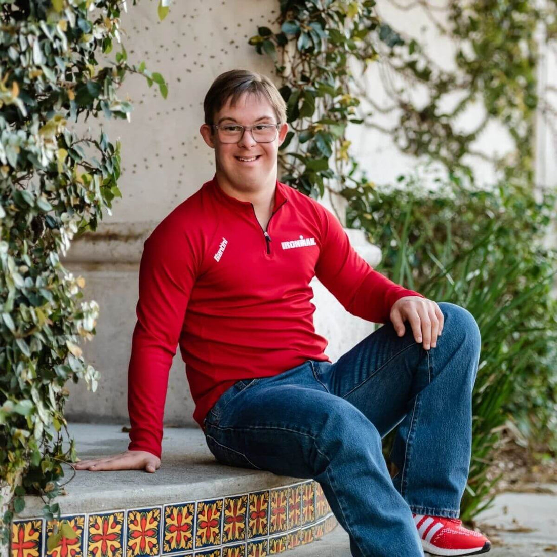 Chris Nikic wearing a red Ironman shirt and sitting outdoors