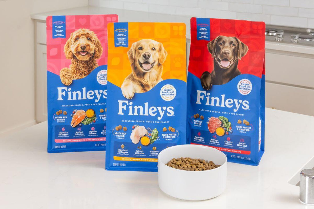 Three packages of Finley's dog food on a kitchen counter with a bowl of kibble.