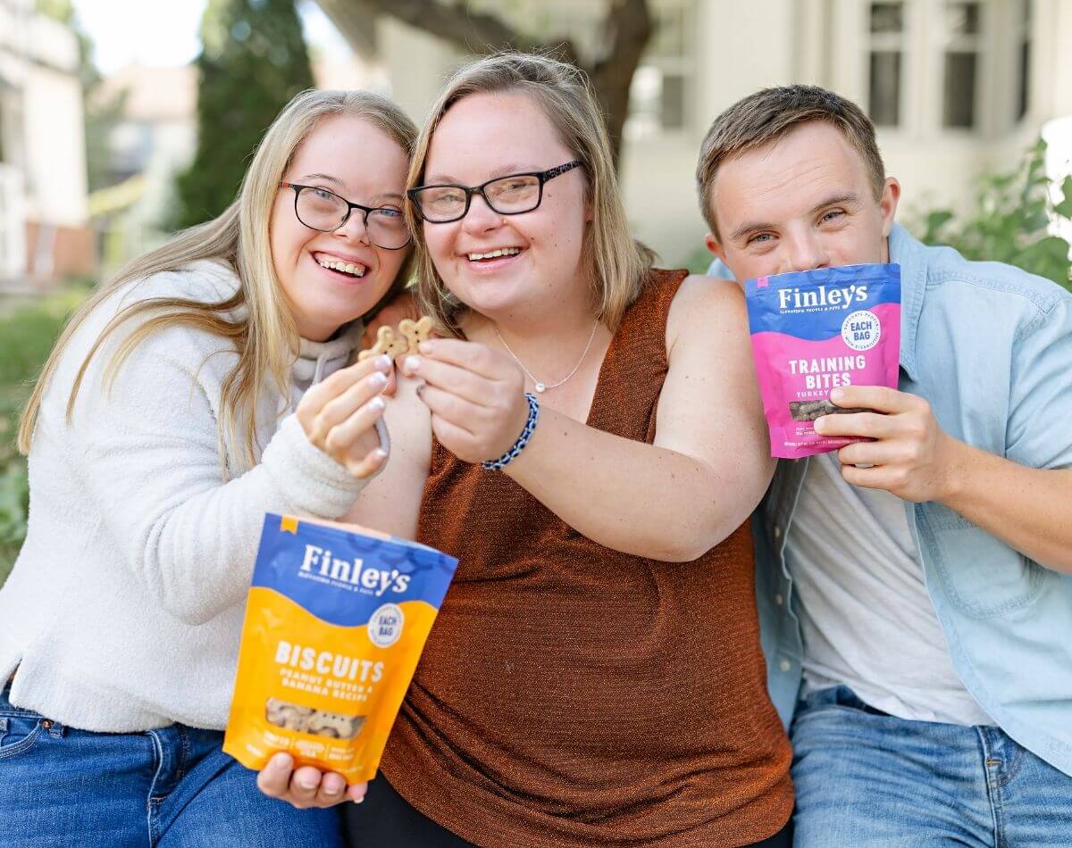 Two women and a man holding bags of Finley's treats outdoors