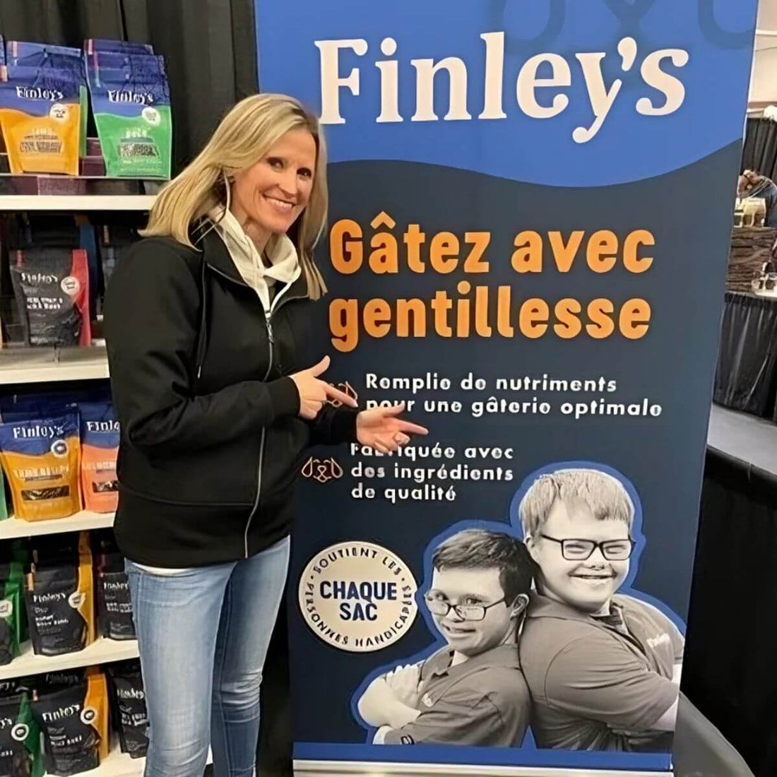 Angie Gallus pointing at a Finley's promotional banner in French