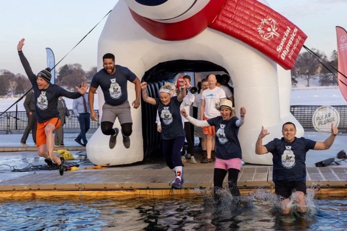 Group of people jumping into water for polar plunge to support Special Olympics Minnesota